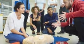 Menschen versammeln sich um Puppe mit Defibrillator