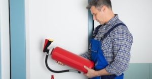 Ein Fachmann hält einen Feuerloescher zur Wartung